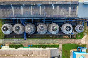 Vista aérea de un conjunto de reactores anaerobios en una instalación industrial, mostrando cinco tanques circulares con ventiladores y tuberías azules, rodeados de estructuras y vegetación.