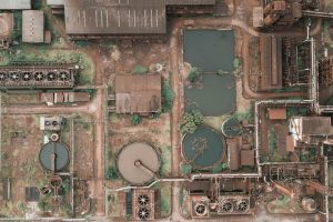 Vista aérea de un reactor anaerobio en una planta industrial, mostrando tanques circulares y estructuras de procesamiento rodeadas de vegetación y tuberías, ilustrando su uso en el tratamiento de aguas residuales.